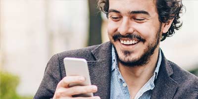 Handsome man reading a message on his mobile device while drinking a coffee