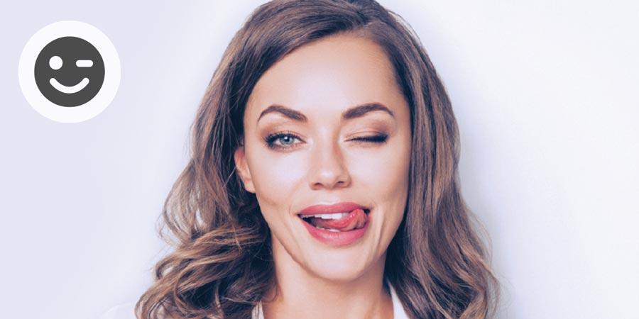 Attractive young woman with long dark blonde hair winking cheekily