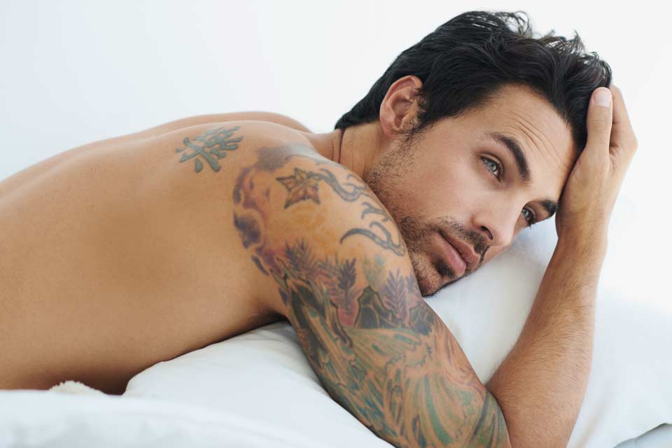 Handsome man with sleeve tattoo lying in bed