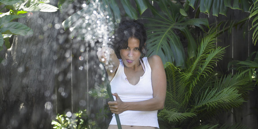 Attractive young woman holding a hose to imply that she is squirting