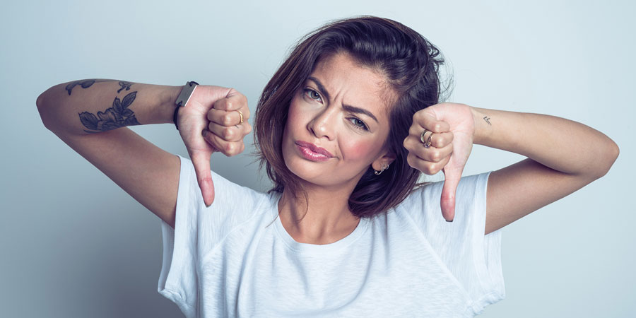 Attractive young woman giving two thumbs down to indicate the things she would not do as a sexpert