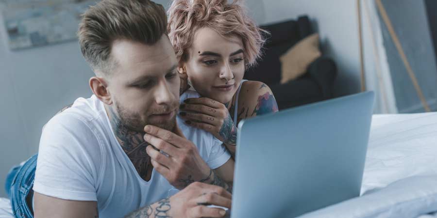 Attractive 20 something couple with tattoos looking at research on their computer about sex drives