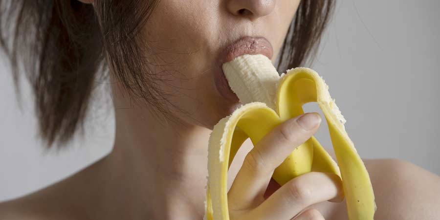 Woman sucking on a banana to represent oral sex on a man's penis 