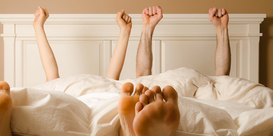 A couple lying side by side with their arms in the air in jubilation 