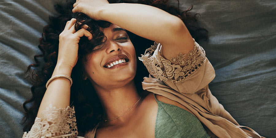 Woman lying in bed looking satisfied and smiling