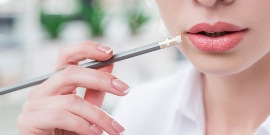 Woman holds a pencil in her hand and ponders what questions to ask her potential date