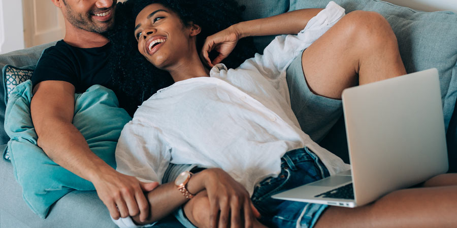 Attractive couple lying on couch playing a game and laughing