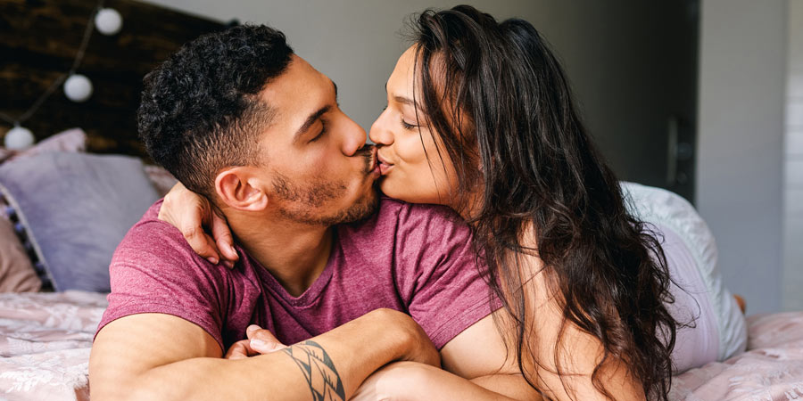Attractive polyamorous couple sharing an intimate moment lying together on a bed